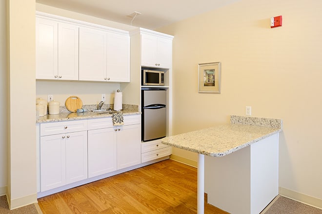 A modern kitchen with white cabinets and built-in appliances.