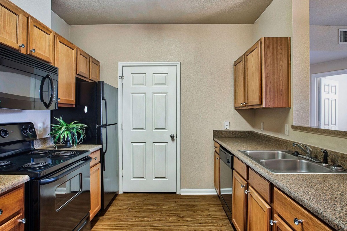A modern kitchen with wooden cabinets, stainless steel appliances, and a sleek countertop.