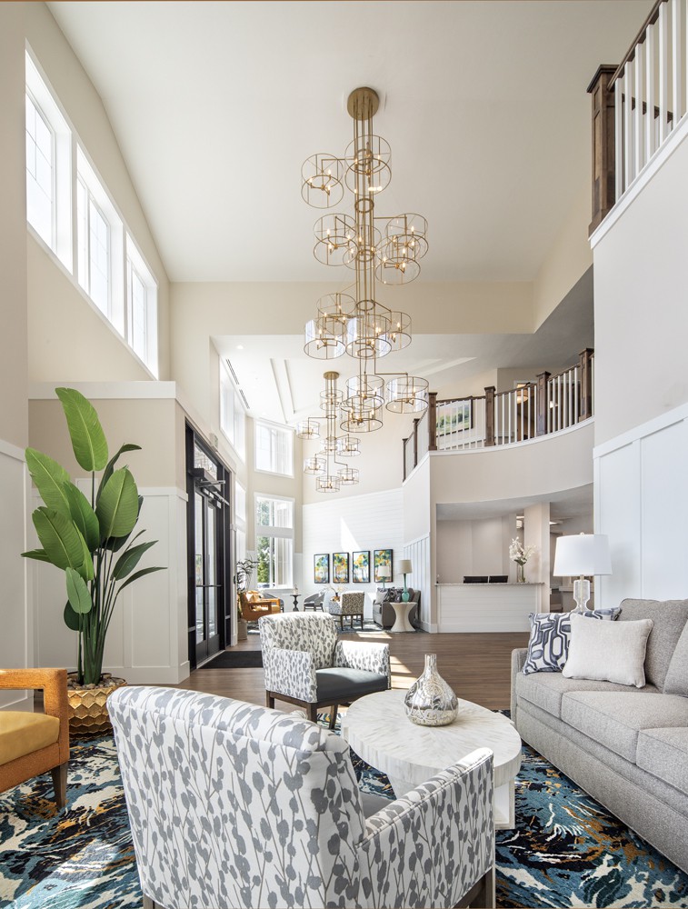 A spacious, modern living room with a luxurious chandelier and abundant natural light.