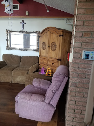 A cozy living room featuring a purple chair, a beige sofa, a wooden cabinet, and decorative elements.
