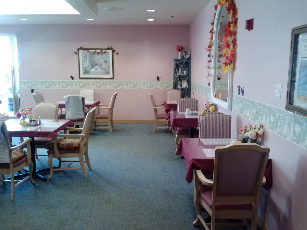 A cozy dining area with pink walls and neatly arranged tables and chairs.