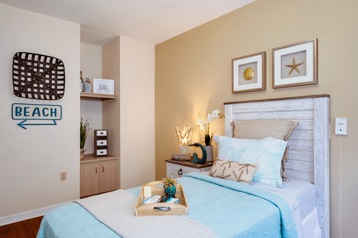 A cozy and well-decorated bedroom with light-colored walls, decorative pillows, and a neatly presented tray on the bed.
