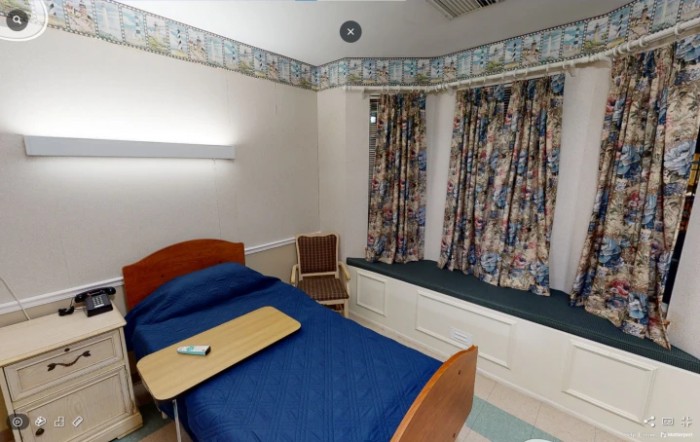 A hospital room with a single bed, curtains, and basic furnishings.