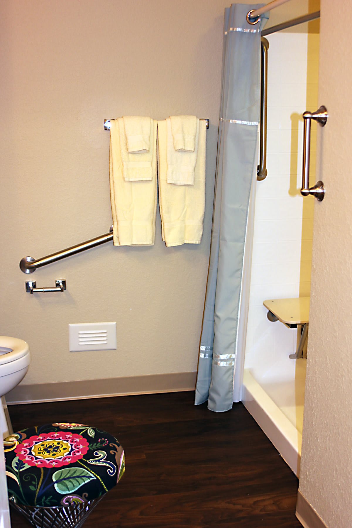An accessible bathroom with handrails and a shower seat.