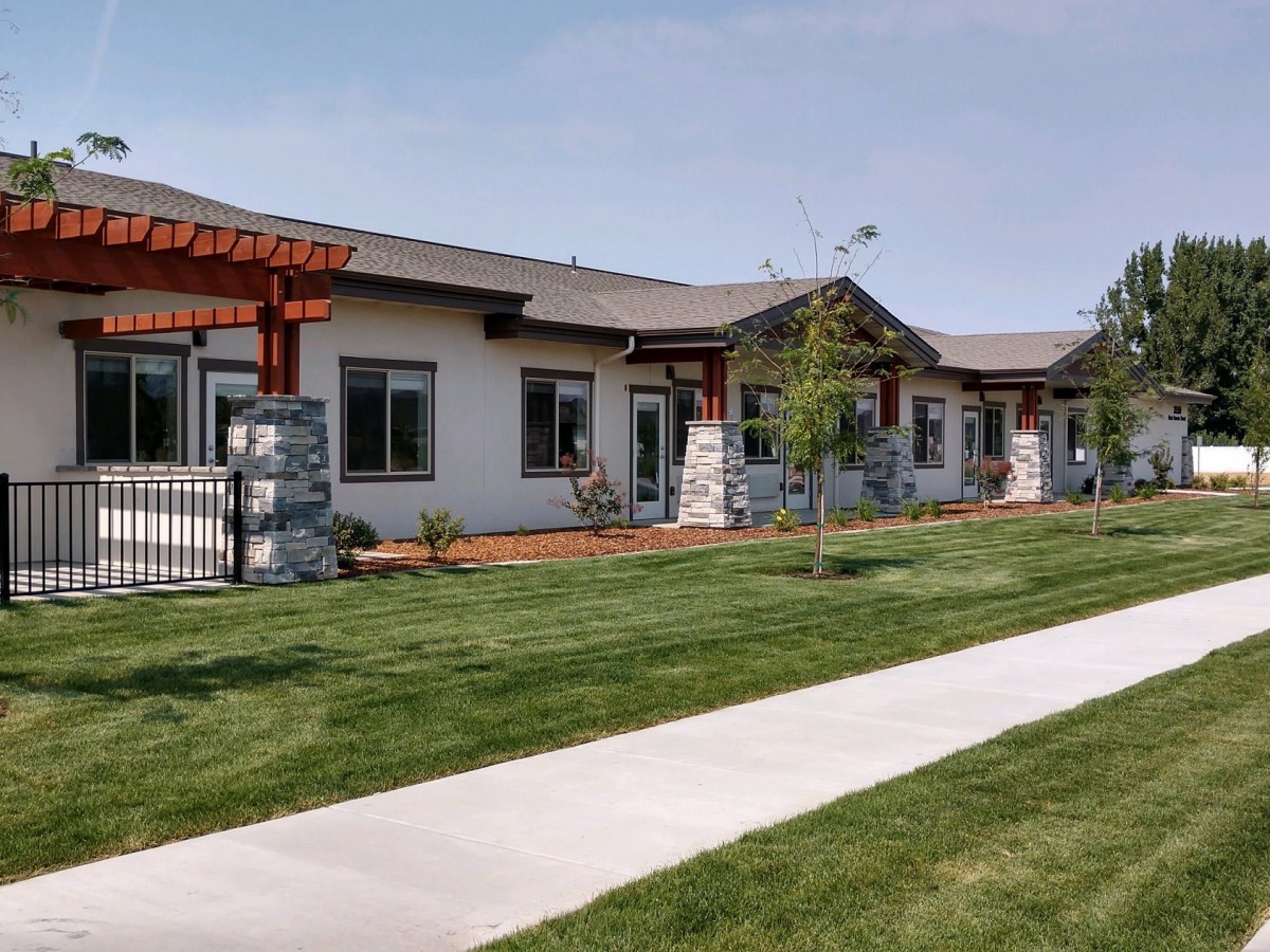 A modern residential building with well-maintained landscaping and a sidewalk.