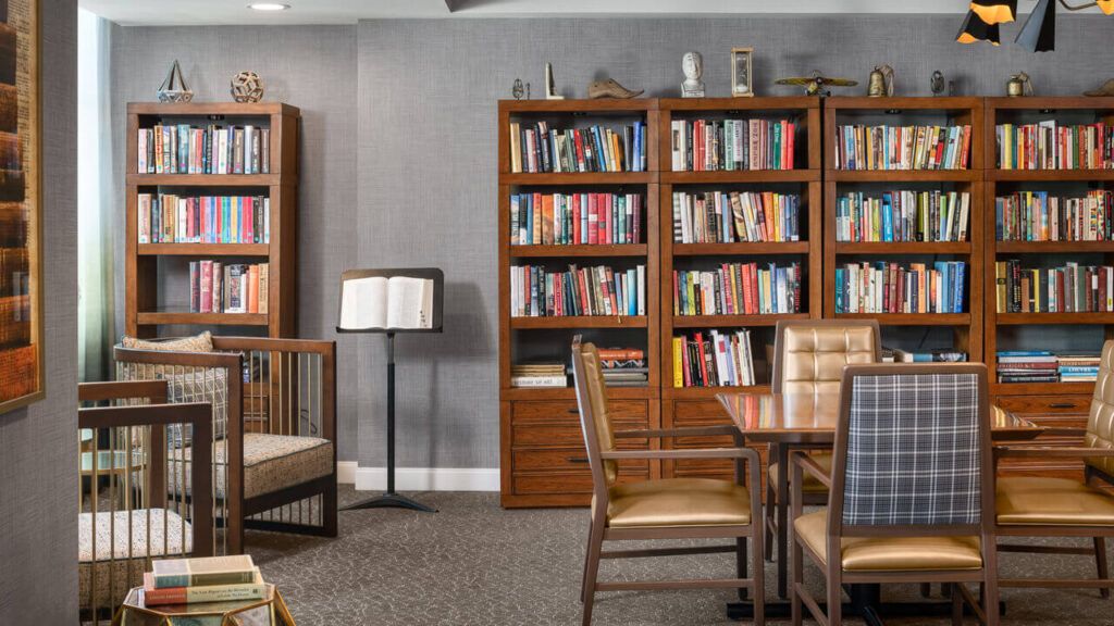 A cozy library space with bookshelves, a reading table, and comfortable chairs.