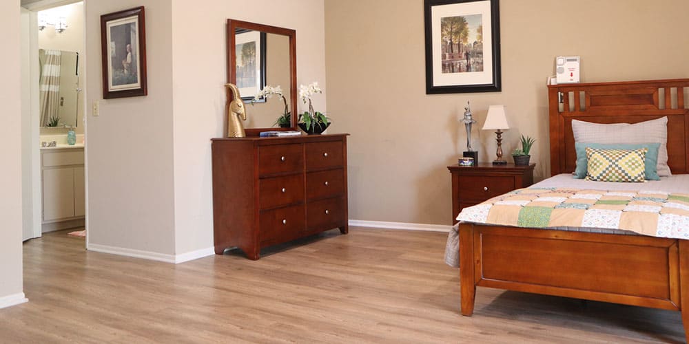 A cozy bedroom with wooden furniture, featuring a dresser with a mirror and elegant decor.