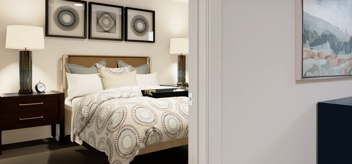 A cozy bedroom featuring a neatly made bed with patterned bedding, artwork on the wall, and a stylish lamp.