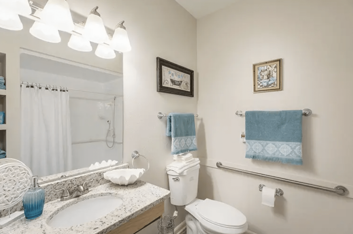 A neatly arranged bathroom with a mirror, sink, toilet, and towels.