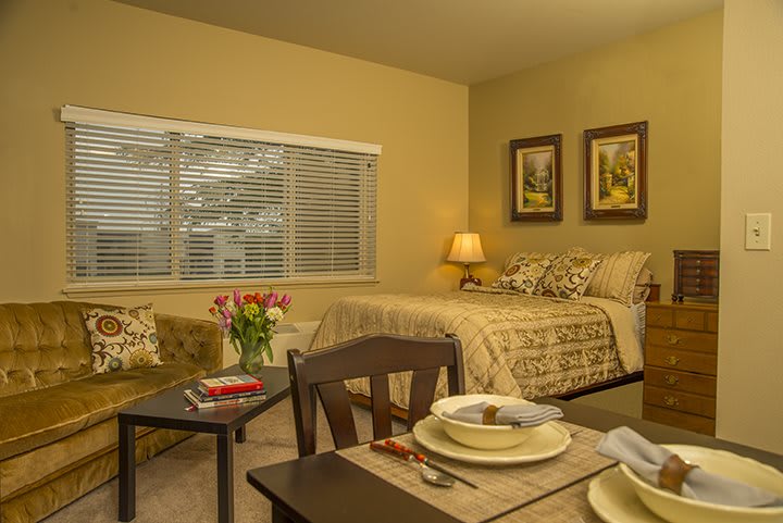 A cozy bedroom with a dining area, featuring warm lighting and elegant decor.