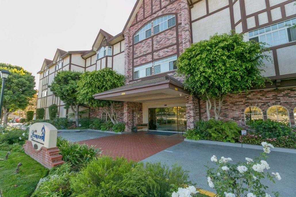 A picturesque entrance to a hotel with a brick facade and lush greenery.