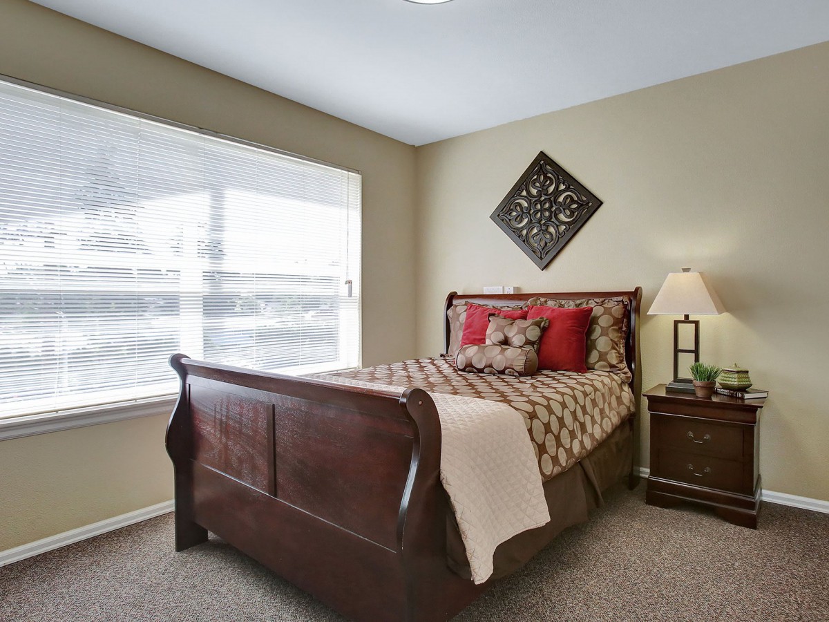 A cozy bedroom with a wooden bedframe, side table, and decorative elements.