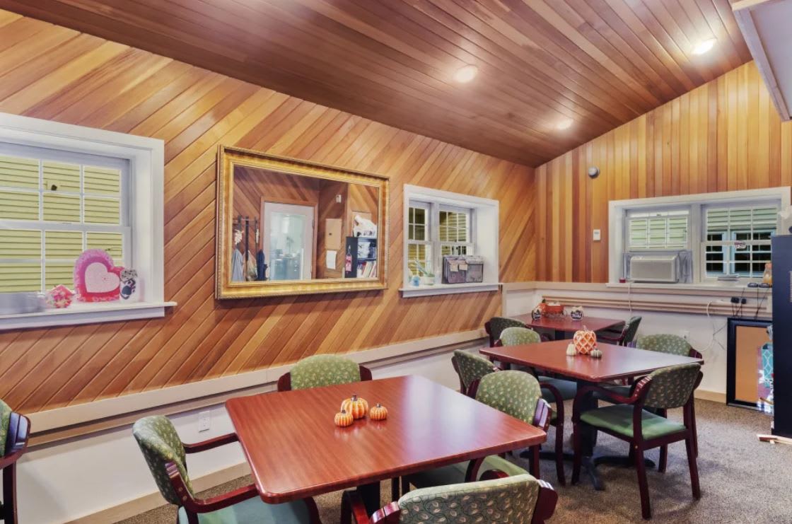 A cozy restaurant interior with wooden walls, featuring tables and chairs set for dining.
