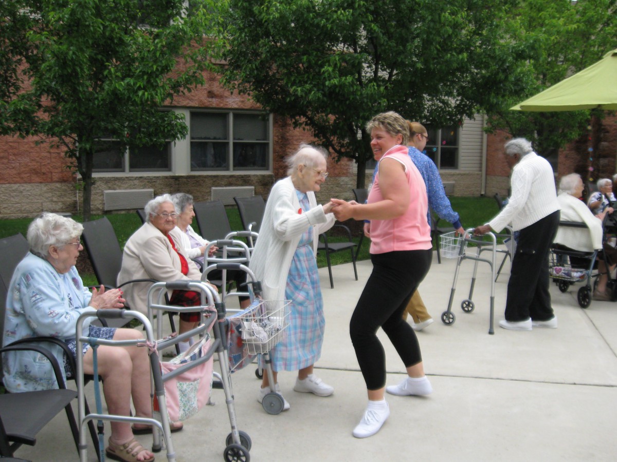 Elderly individuals enjoying a dance session outdoors at a care facility.