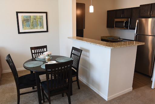 A modern dining area connected to the kitchen, featuring a round table and black chairs.