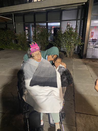 A loving moment shared between family members in a wheelchair, providing warmth and comfort on a chilly night.