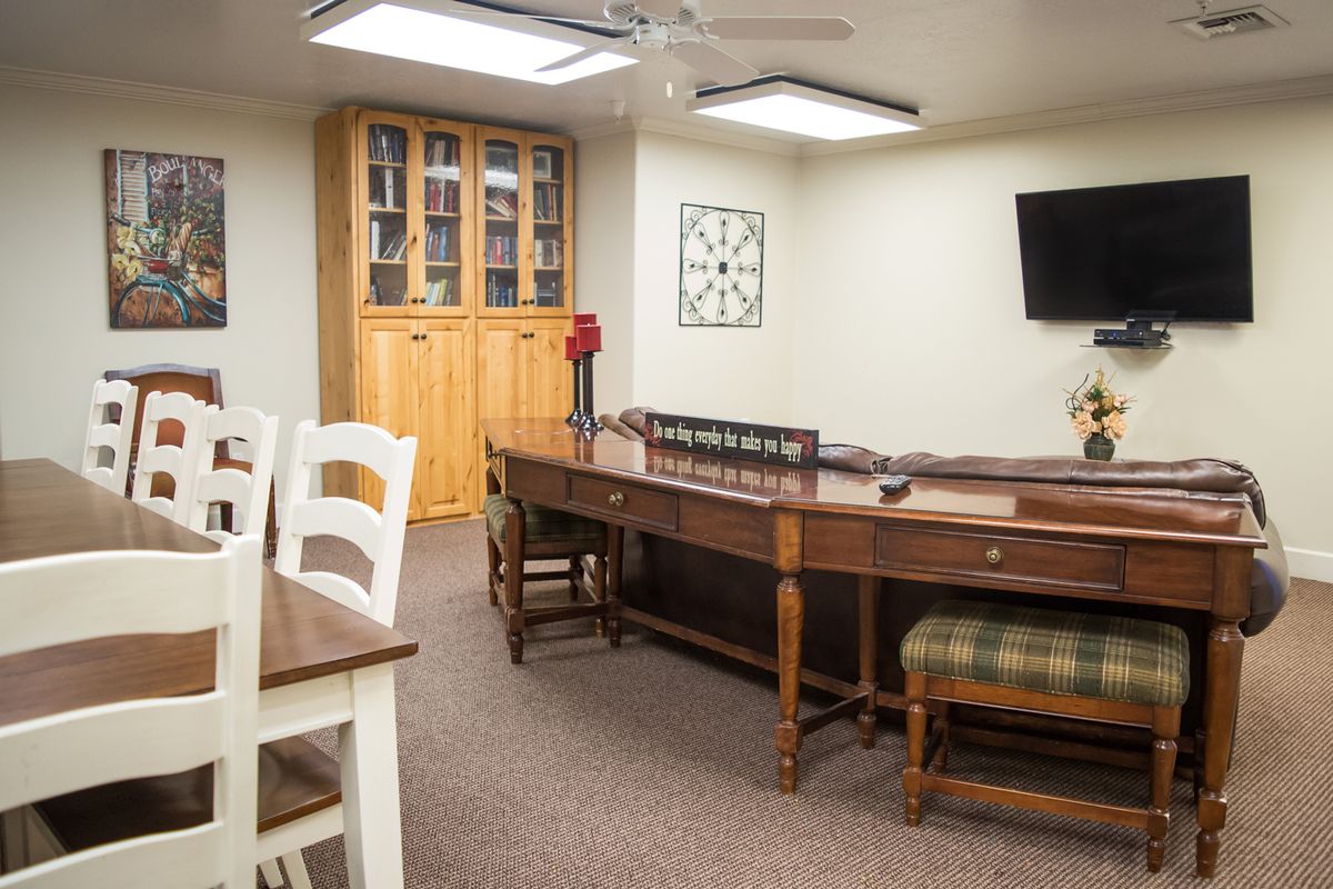 A well-appointed office space featuring a wooden conference table, chairs, a bookshelf, and a TV.