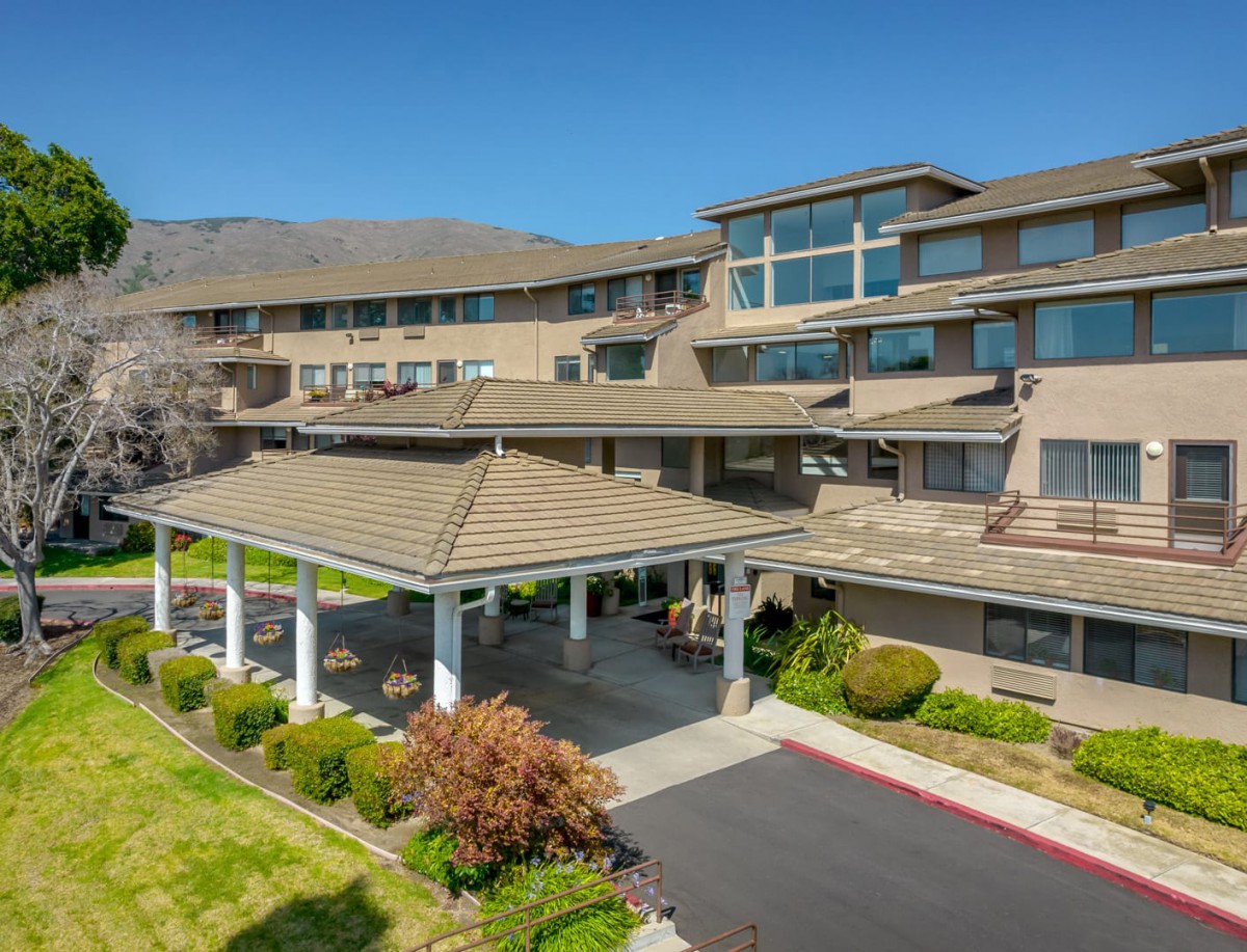 A modern residential building with a landscaped entrance under a clear blue sky.