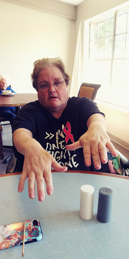 A person showing their hands while seated at a table, wearing a shirt that promotes health awareness.