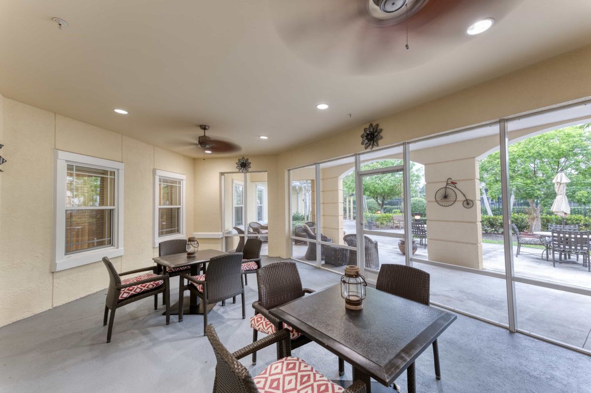 A cozy indoor seating area with tables and chairs arranged near large windows and doors leading to a patio.