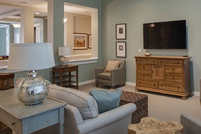A cozy and modern living room with a sofa, armchair, wooden furniture, and a wall-mounted television.