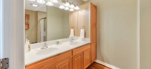 A well-lit bathroom featuring a double vanity with wooden cabinetry and white countertops.