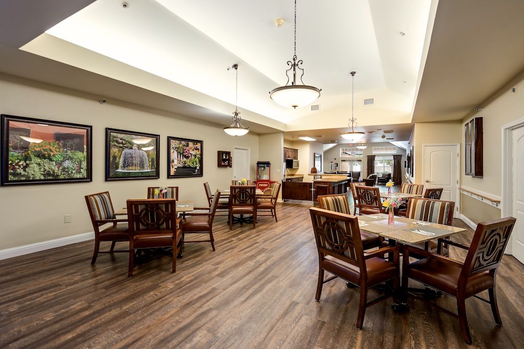 An elegant dining area with wooden flooring, furnished with tables and chairs, and adorned with wall art and ceiling lights.