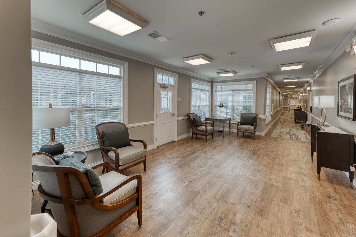 A bright and inviting lobby area with wooden floors, featuring comfortable seating and large windows.