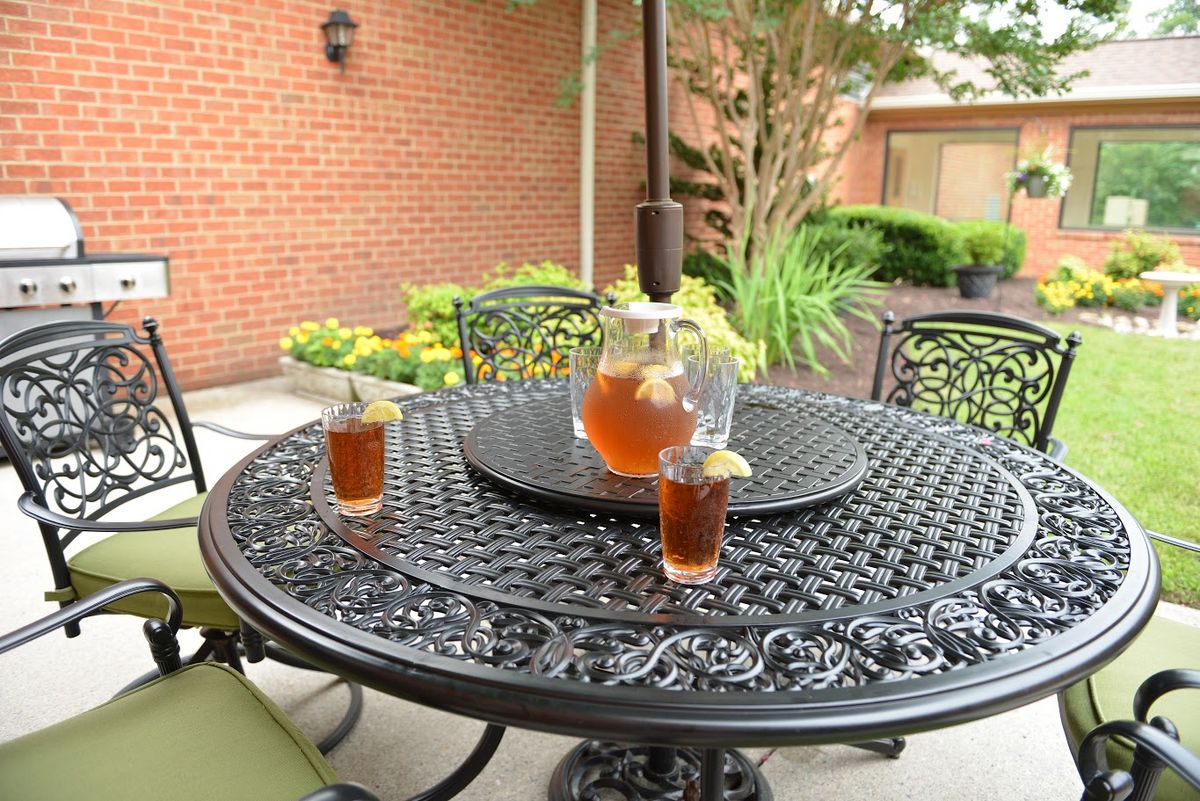 A refreshing pitcher of iced tea with glasses on a patio table.