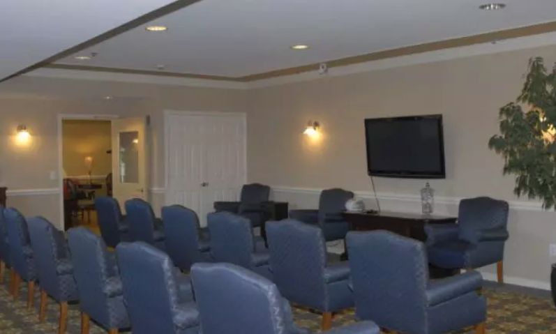 A small conference room with rows of chairs facing a television.