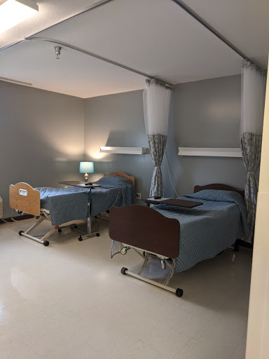 A view of a shared patient room in a healthcare facility, featuring two hospital beds and basic furnishings.
