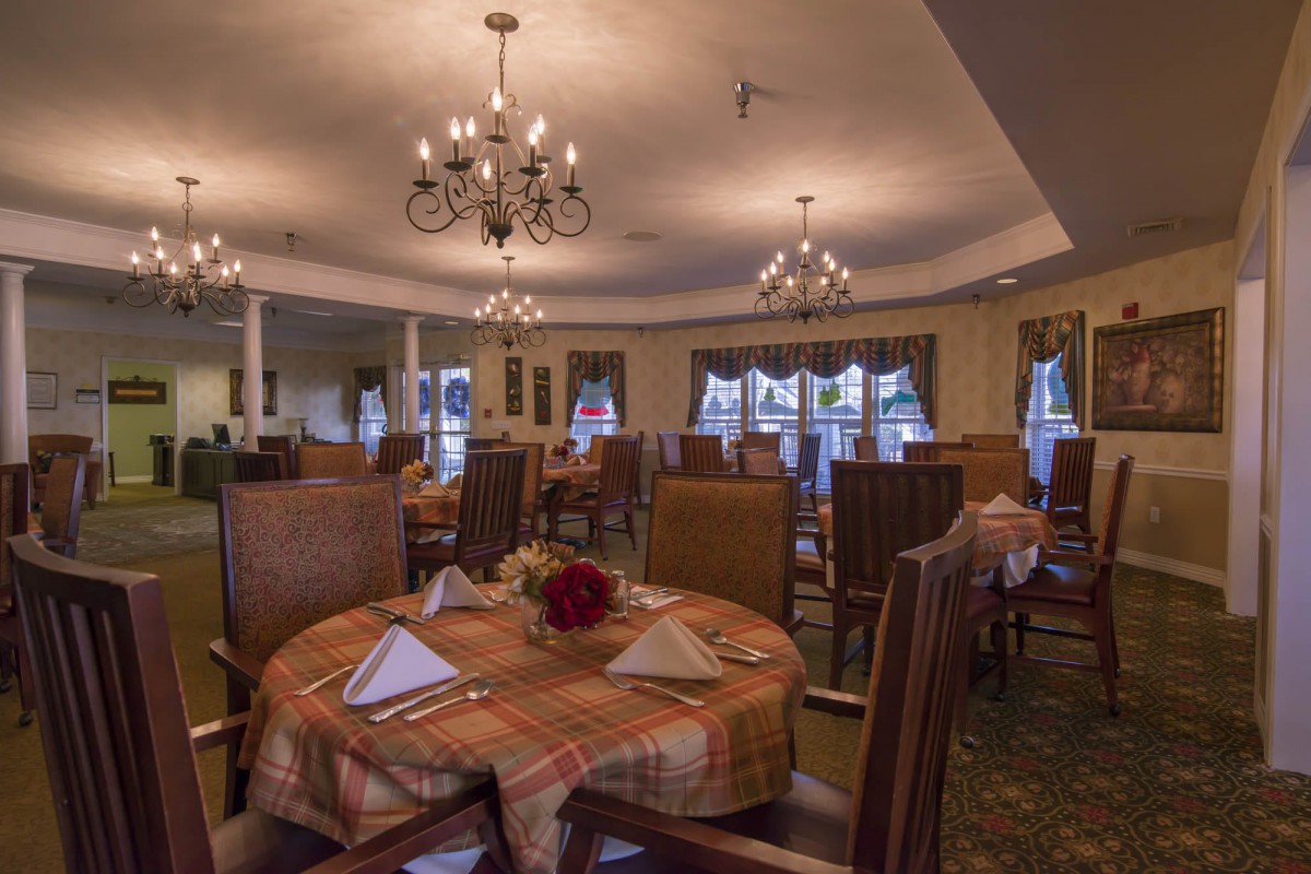 An elegant dining room with neatly set tables and chandeliers.