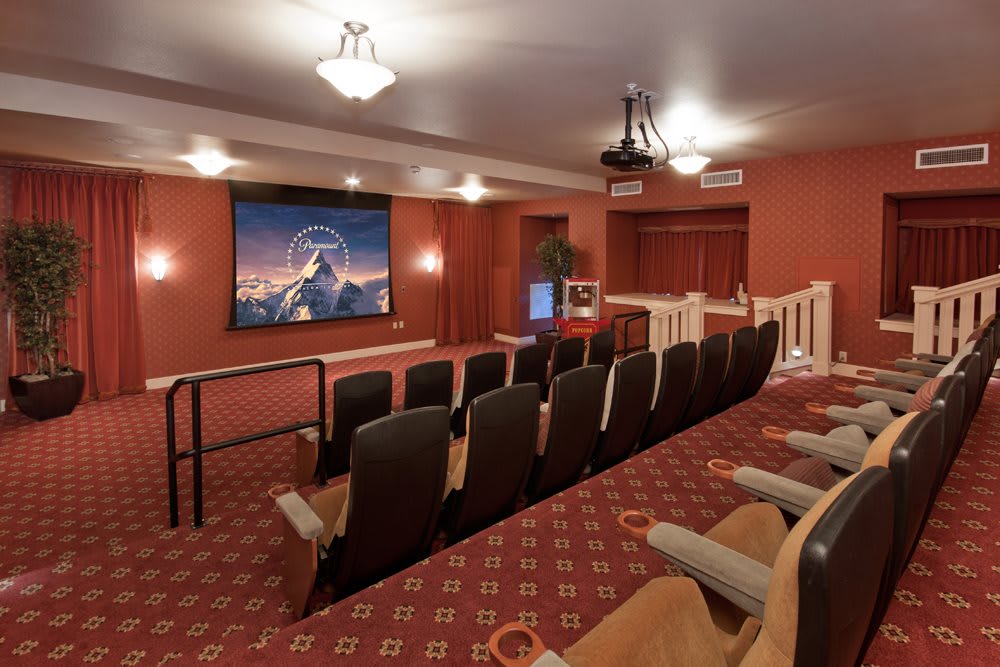 A cozy home theater setup with multiple rows of seating and a large screen displaying a movie.