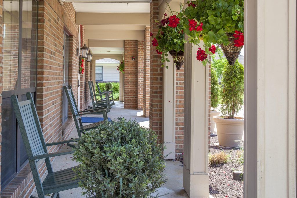 A cozy porch with chairs and hanging plants, perfect for relaxing.