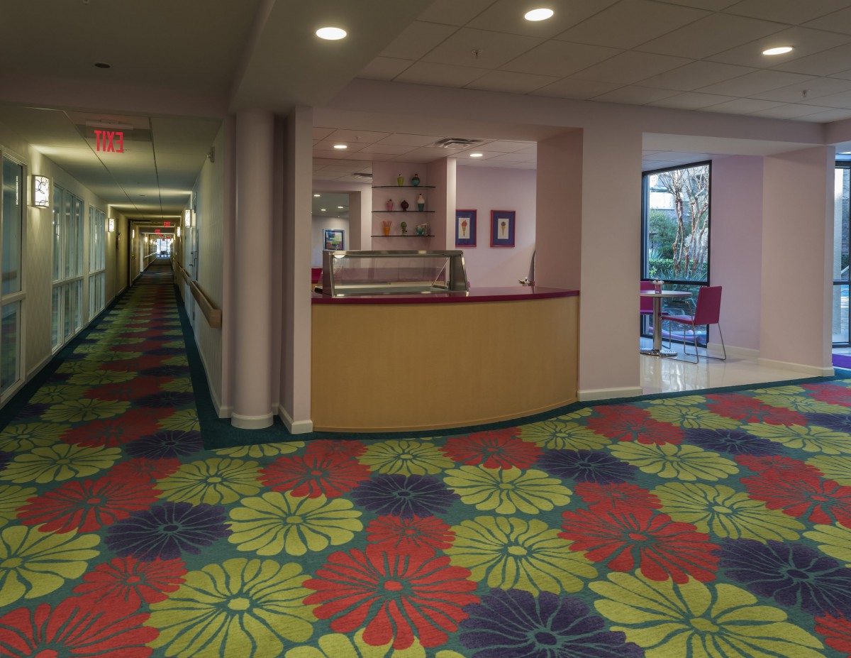 A hotel hallway with a colorful patterned carpet and a lobby area.