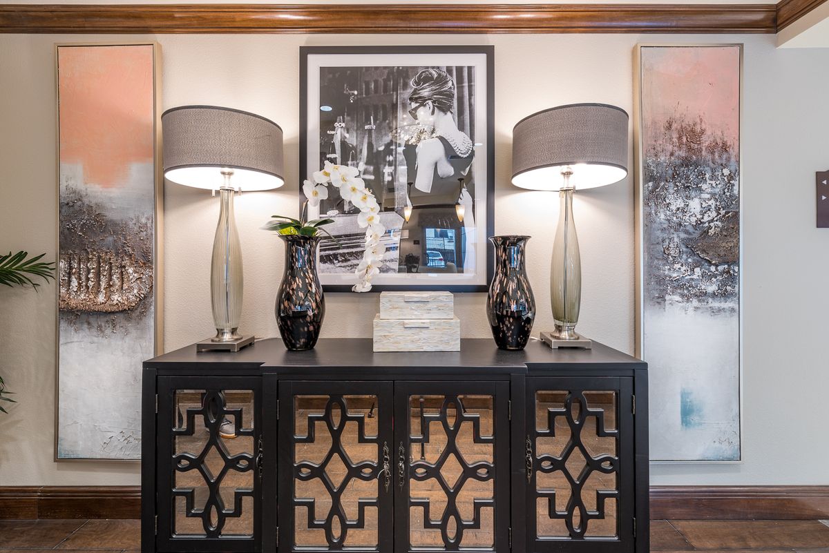 Elegant interior display featuring a console table adorned with vases and matching table lamps, complemented by framed artwork.