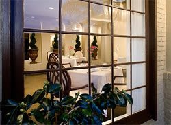 Elegant dining area viewed through a window with decorative plants.