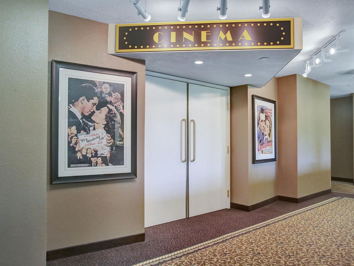 The entrance to a cinema, featuring movie posters on the walls and a sign above the doors.