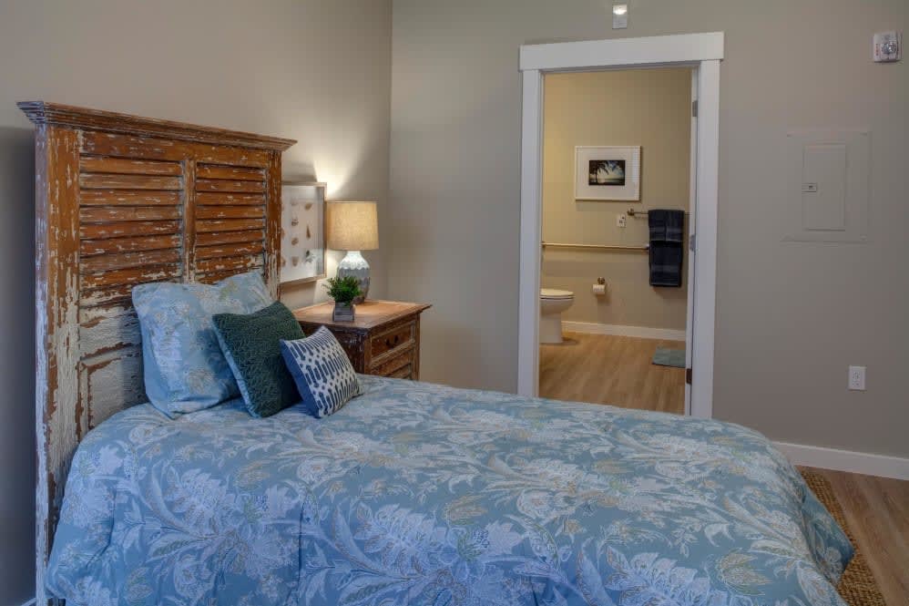 A cozy bedroom with a view into the bathroom through an open doorway.