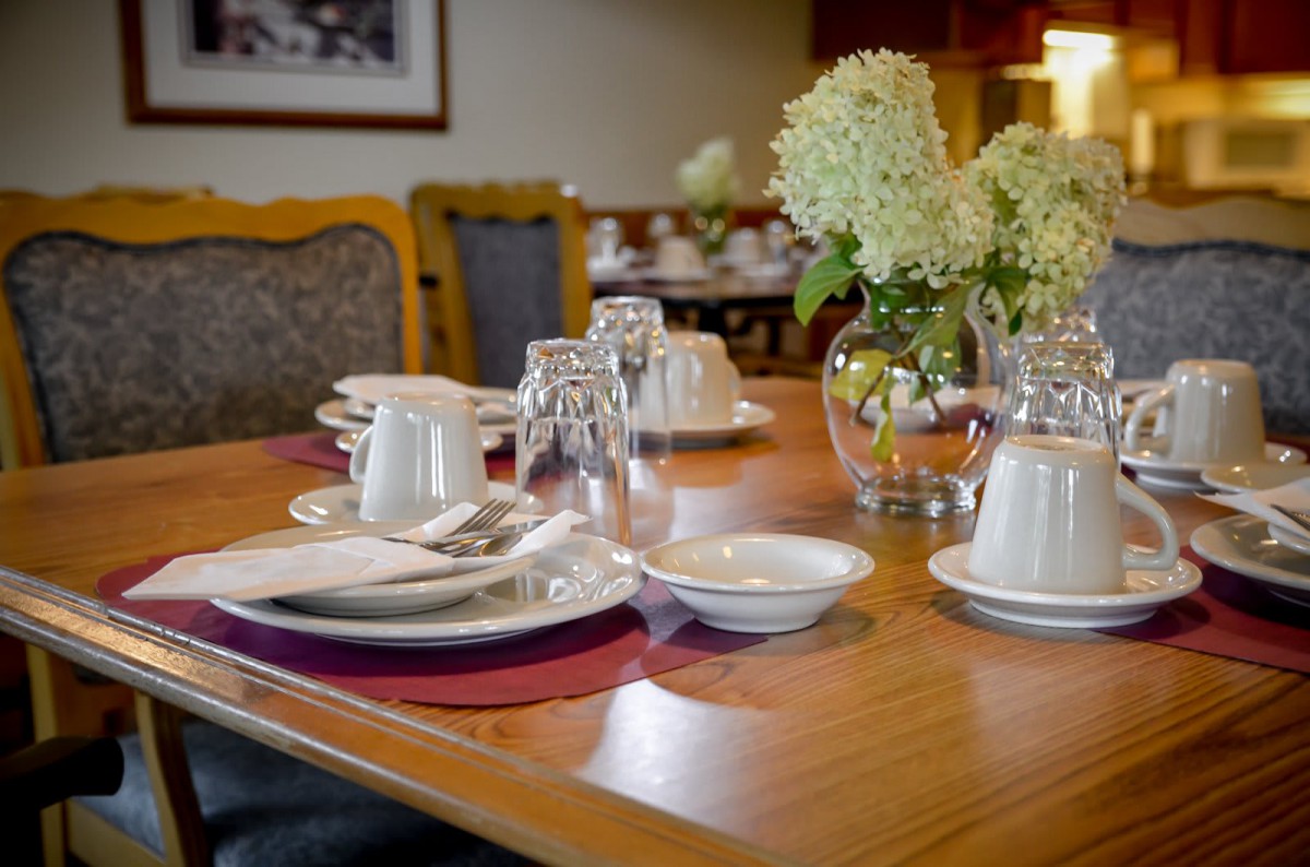 A beautifully set dining table with plates, glasses, and a vase of flowers in a restaurant setting.