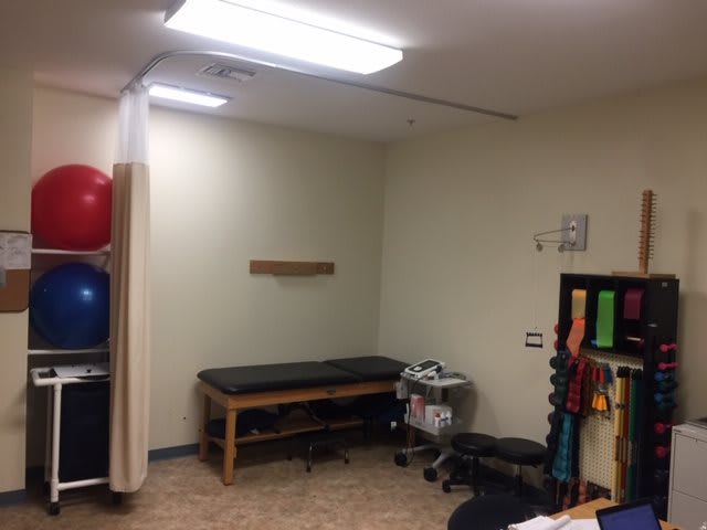 A physical therapy room with a treatment table and various rehabilitation equipment.