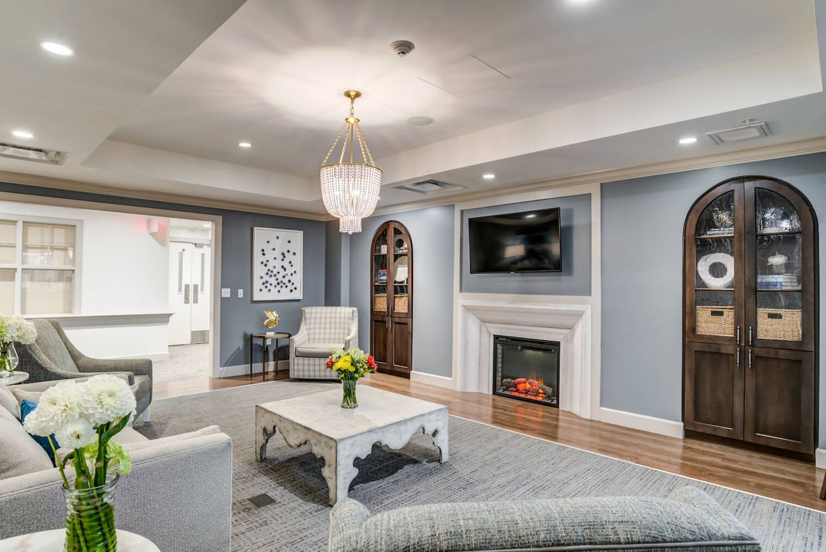 A modern living room with elegant decor, featuring a chandelier, fireplace, and comfortable seating.