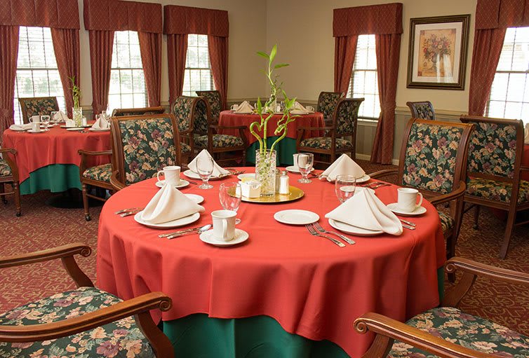 A beautifully set dining table with red tablecloths and elegant folded napkins in a formal restaurant setting.