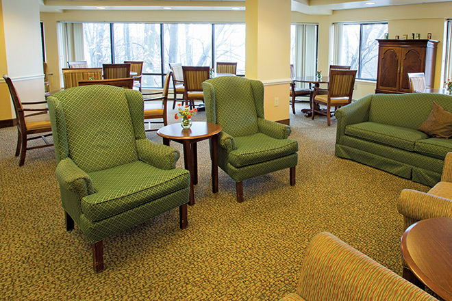A cozy living area with green armchairs and large windows.