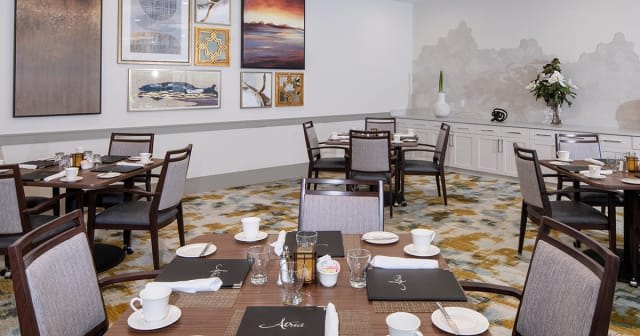 An elegant dining area with neatly arranged tables and wall artwork.