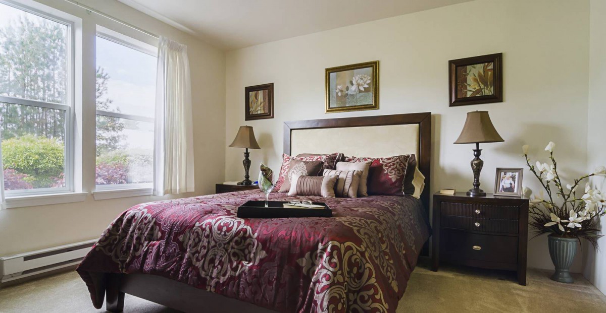 A cozy bedroom with a decorative bedspread, matching pillows, and framed artwork on the walls.