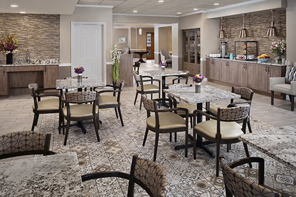 A modern cafe interior with tiled flooring and neatly arranged tables and chairs.
