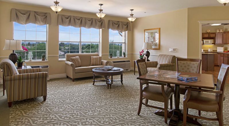 A cozy living room interior with sofas, a coffee table, and large windows providing natural light.