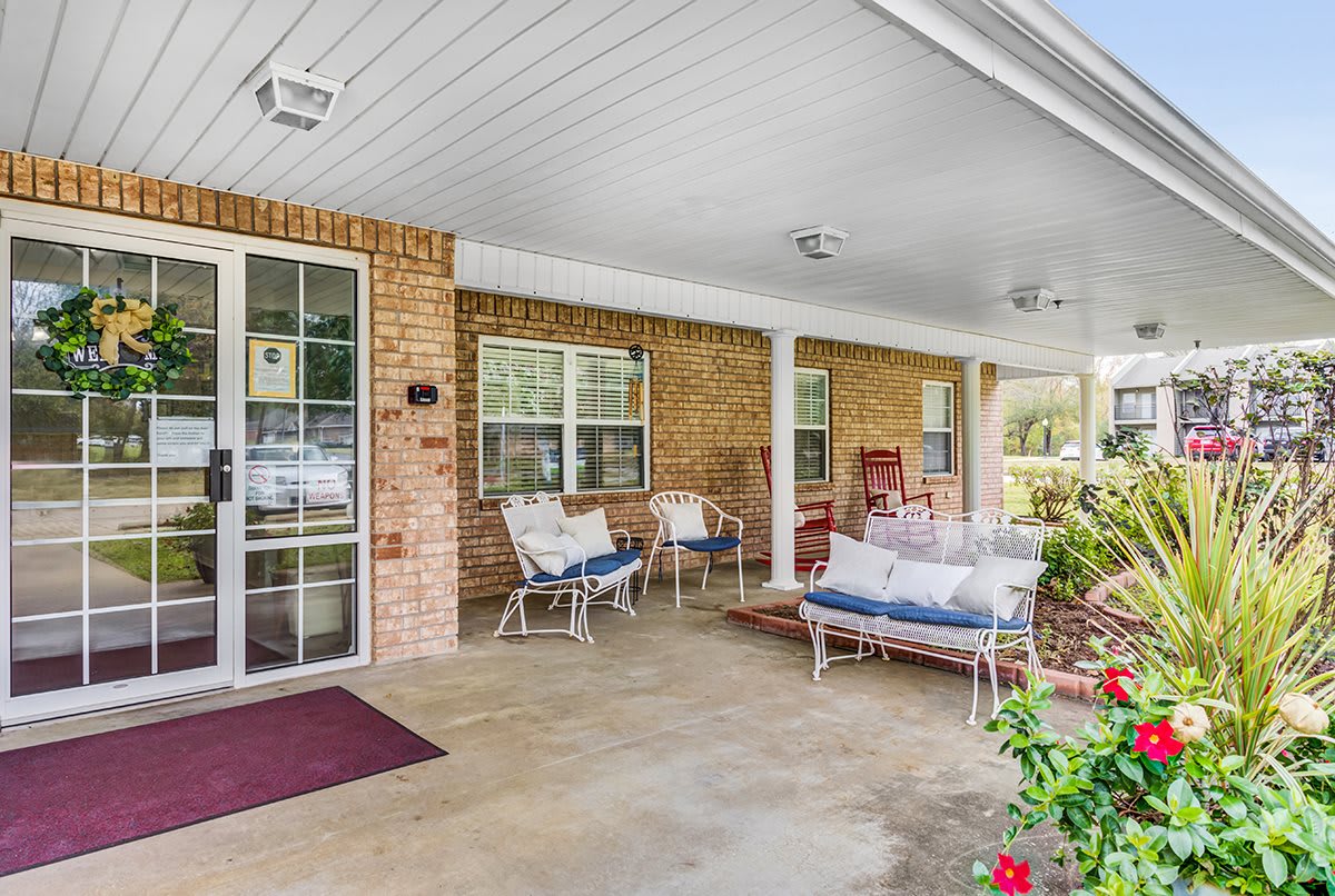 A cozy covered porch with comfortable seating and a brick wall, perfect for relaxation.