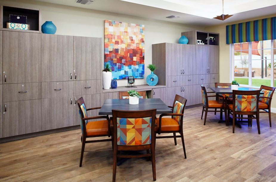 A modern dining area with colorful artwork and vibrant chairs.